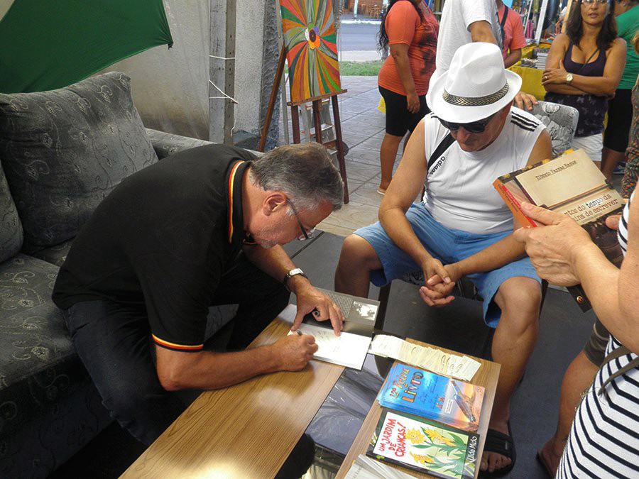 Tibério Vargas Ramos autografa Contos do tempo da máquina de escrever para Vicente, turista espanhol